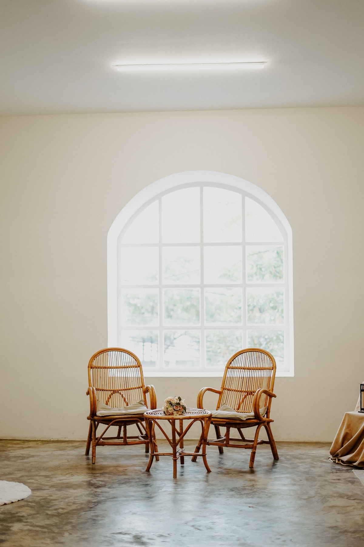 Zwei Rattanstühle vor einem großen Bogenfenster im Besprechungsraum.