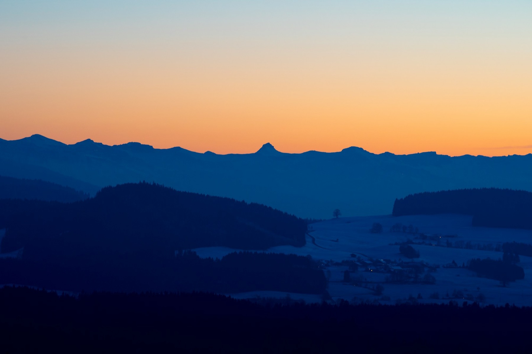 Allgäuer Bergkette im Abendlicht, im Vordergrund verschneite Hügel