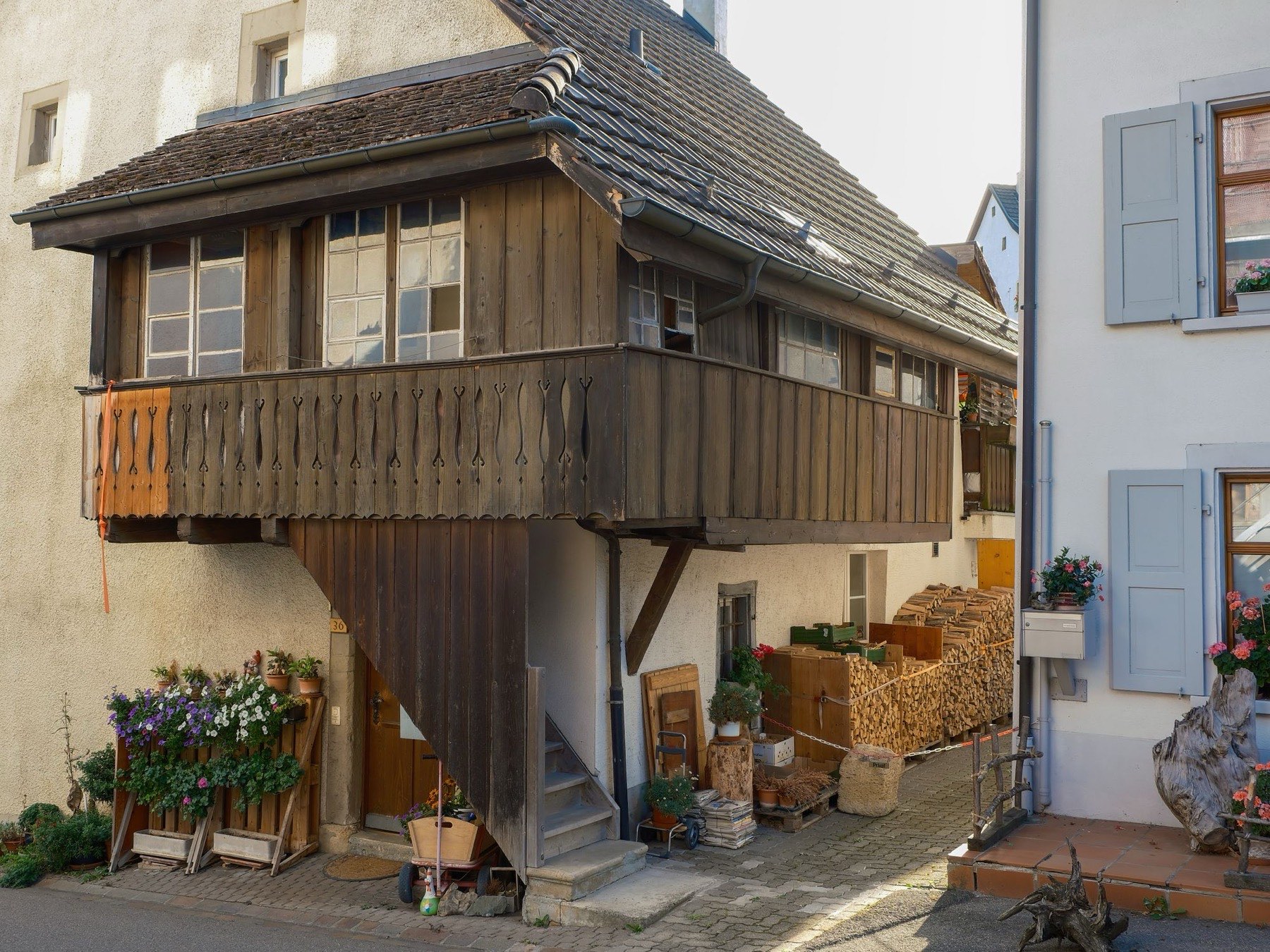 Altes Wohnhaus mit hölzerner Laube und Brennholz vor dem Eingang