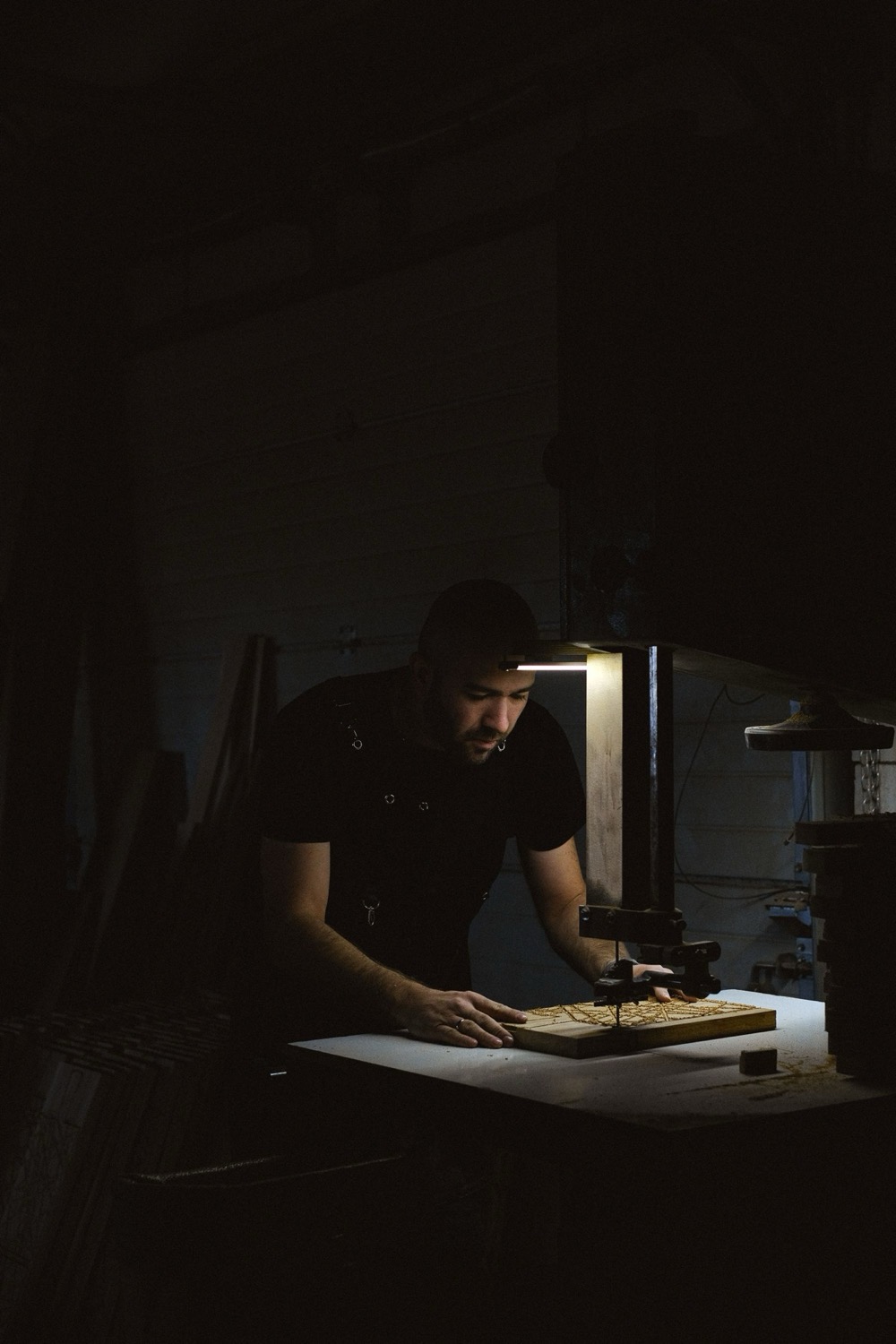 Handwerker arbeitet im Lichtkegel an einer Werkbank